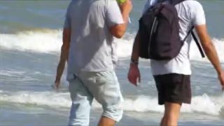 Topless legal age teenager playing at beach in water